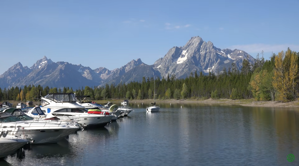 ships on the lake near the coast with trees, and mountains far away